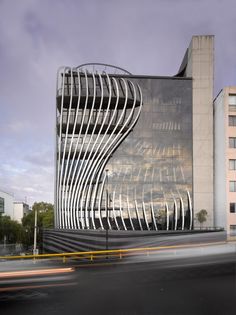 an artistic building is shown in the middle of a street with cars passing by it