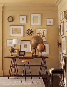 a room with many pictures on the wall and a desk in front of it that has a chair next to it