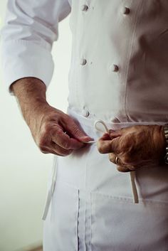 a chef is holding scissors in his hands while wearing a white coat and bracelets