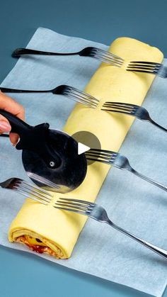 a person is holding forks and knives over some food wrapped in napkins