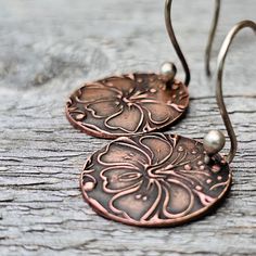 These tiny flower copper earrings are a light and fun pair of everyday earrings.  The photos have been enlarged to show detail. Please see the numeric dimensions.  A floral design rolled out in a texture from precious metal clay that has been sanded, filed, and fired in a high-temperature kiln. The earrings have been oxidated and then brushed to show the detail. The diameter of the discs is .75  and the length of the earrings from the top of the ear wire to the bottom of the disc is 1.5 inches, Torch balled ear wires are hand-formed from sterling silver. Precious metal clay now contains recycled copper so these earrings are eco-friendly! Please contact me with any questions. Thank you for looking! Pam :) Back to this shop-----> http://www.etsy.com/shop/adorned7 Copper Drop Earrings With Flower And Ear Wire, Copper Drop Flower Earrings With Ear Wire, Nickel-free Copper Flower Drop Earrings, Handmade Copper Flower Earrings, Copper Drop Flower Earrings As Gift, Adjustable Copper Flower Earrings, Handmade Copper Flower Drop Earrings, Handmade Bronze Flower Earrings For Gift, Pmc Earrings