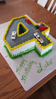 a birthday cake with cars on it sitting on top of a table