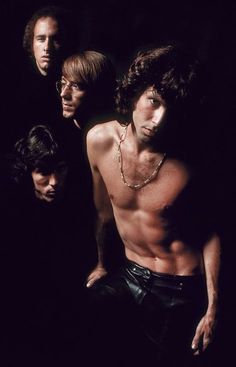 three shirtless men standing in the dark with their hands on their hipss and one is looking at the camera