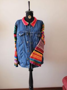 a blue jean jacket with multicolored sleeves on a mannequin head stand