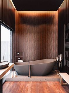 a large bath tub sitting inside of a bathroom next to a wooden flooring wall