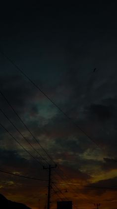 the sun is setting behind power lines and birds are flying in the sky above them