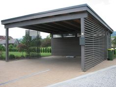 a large metal carport sitting on the side of a road next to a lush green field