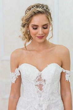 a woman wearing a wedding dress with an off the shoulder neckline