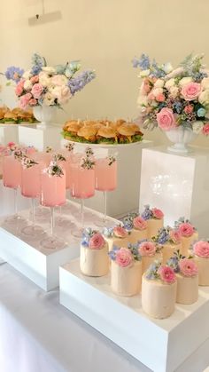 there are many desserts and drinks on the buffet table at this wedding reception with flowers in vases