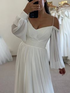 a woman taking a selfie wearing a white dress and holding a cell phone in her hand