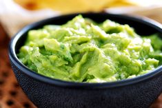 a black bowl filled with guacamole and chips