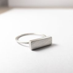 "This sterling silver bar ring is a very sleek modern minimalist ring. The ring band is made from sterling silver and is 1 mm thick with a slightly hammered finish. The rectangular bar on it is sterling silver and has a smooth brushed finish. The bar is approximately 1 cm (3/8\") long, 4 mm wide, and 2 mm thick. DETAILS - 925 sterling silver band - 1 mm thick band - Bar approx. 2 mm x 4 mm x 10 mm  Sizing - use the chart in the last photo to check your ring size. Please note that the band is onl Minimalist Sterling Silver Rectangular Ring, Minimalist Open Band Midi Rings, Minimalist Rectangular Stackable Rings, Minimalist Everyday Stackable Rings, Minimalist Midi Rings As Gift, Minimalist Sterling Silver Stackable Rectangular Rings, Minimalist Sterling Silver Rectangular Stackable Rings, Silver Minimalist Stackable Rings, Minimalist Sterling Silver Stackable Rings