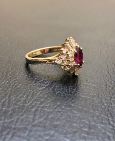 a close up of a ring with a red stone in the middle and two white stones around it