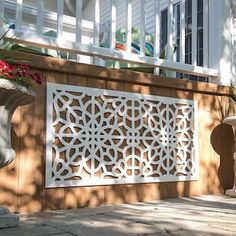 an outdoor area with potted plants and a decorative screen on the side of a house