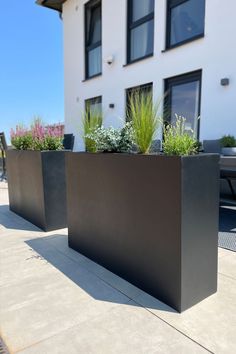 two black planters sitting on the side of a building