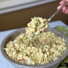 a person holding a spoon full of macaroni salad