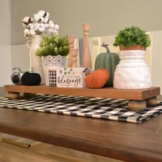 a wooden table topped with vases filled with plants and other decorations on top of it