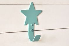 a blue metal hook on the side of a white wooden wall with a star design