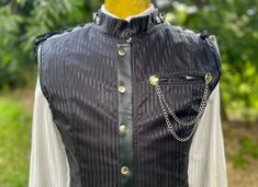 A super cool 1990's vintage gothic steampunk style vest. A black on black pinstripe satin fabric with black faux leather trims and silver hardware. The vest has boning to give it structure and features a high neck with a stand collar. The front has a zip closure hidden by a placket with large metal snap buttons. Both shoulders and centre back have lace up seams - allowing for an adjustable fit. There is a chest pocket with medallion and chain detailing. Please note white marks on the inside lini Steampunk Vest, Pirate Cosplay, Steampunk Pirate, Goth Steampunk, Style Steampunk, Style Vest, Washing Powder, Black Goth, Gothic Steampunk