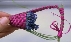 someone is holding a piece of woven material with pink and blue flowers in the middle