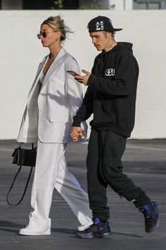 a man and woman walking down the street holding hands