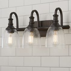 three light bathroom fixture with clear glass shades on the top and bottom lights in an old - fashioned style