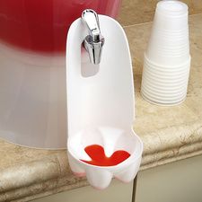 a white cup with red liquid in it sitting next to a faucet