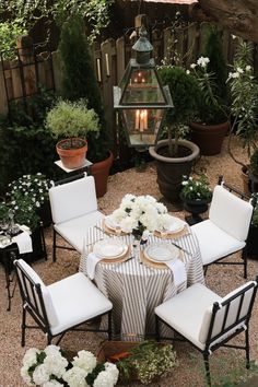 an outdoor dining area with white flowers and potted plants