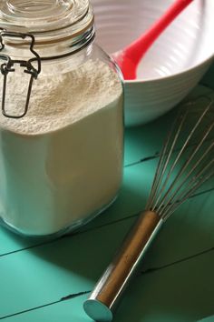 a glass jar filled with white powder next to a whisk