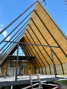 a wooden building that is under construction with metal bars on the roof and two ladders in front of it