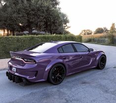 the purple sports car is parked on the side of the road in front of some bushes