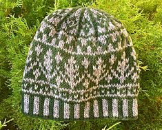 a green and white knitted hat sitting on top of a tree