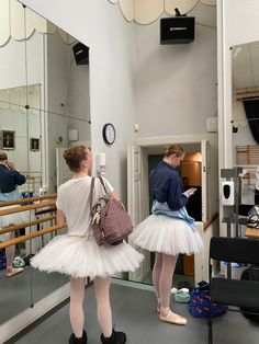 two ballerinas in tutu skirts are looking at their reflection in the mirror