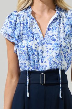 Enhance your casual wardrobe with the Camellia Floral Jewel Split Neck Top! It has a beautiful ditsy blue floral print on a white background. Short sleeves and a split neckline with adjustable tie around shape this top. Easy to pair up with white pants and blue shoes of your choice. - Split neck- Ruffle trim- Flowy sleeves- Lined- Color: Wht Blue MultiSize + Fit - Model is 5'8" and wearing size XS- Measurements taken from size S - Chest: 20 3/8"- Length: 24 1/2" Fabric Self: 100% Polyester, Lini White Floral Top, Iphone Instagram, Blue Floral Top, Flowy Sleeves, Blue Floral Print, Neck Ruffle, Work Outfits Women, White Pants, Wide Leg Jumpsuit