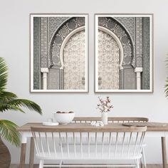 two framed art prints on the wall above a dining room table with chairs and vases