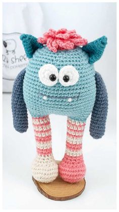 a crocheted stuffed animal with big eyes and pink socks on it's legs