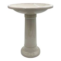 a white pedestal with a birdbath on it's top and the base is made out of concrete