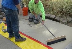 two men are working on a concrete slab