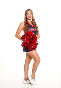 a woman in a cheerleader uniform posing for a photo with her pom poms