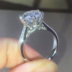 a person is holding a diamond ring in their hand, with the center stone on it's side