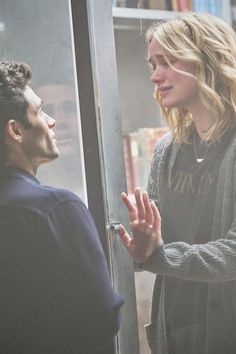 a man and woman standing next to each other in front of a glass door talking