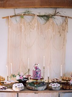 a table topped with cakes and cupcakes next to a wall hanging from the ceiling