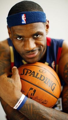 a man holding a basketball in his right hand and wearing a headband on top of it