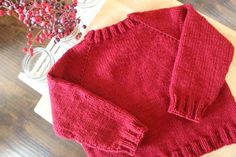 a red sweater sitting on top of a wooden table