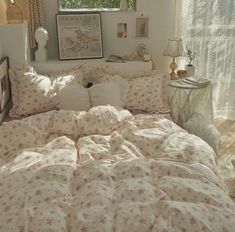 a bed with pink and white flowers on it in a bedroom next to a window