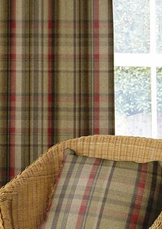 a wicker chair sitting in front of a window with plaid fabric on the curtains