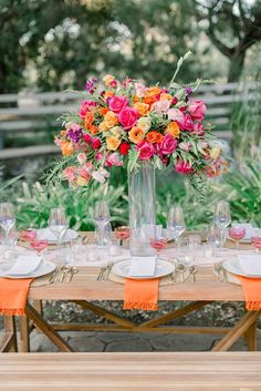 the table is set with flowers and wine glasses on it, along with place settings