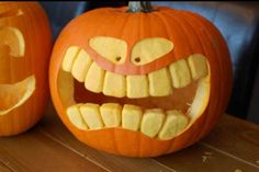 two carved pumpkins with faces and teeth on them