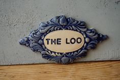 a blue and white sign that reads the loo on it's side wall