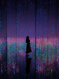 a woman standing in front of a wall covered with lights